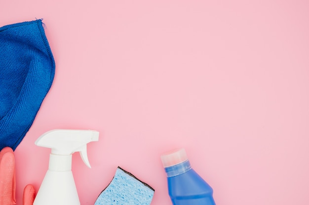Collection of house cleaning supplies on pink backdrop