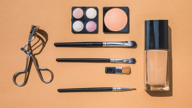 Collection of make up and cosmetic beauty products arranged on ochre background