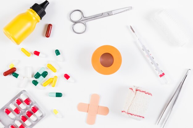 Коллекция медицинской бутылки; таблетки; повязка и термометр, изолированные на белом фоне