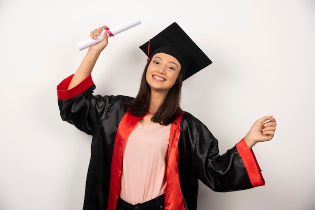 College graduate female in gown standing on white background.