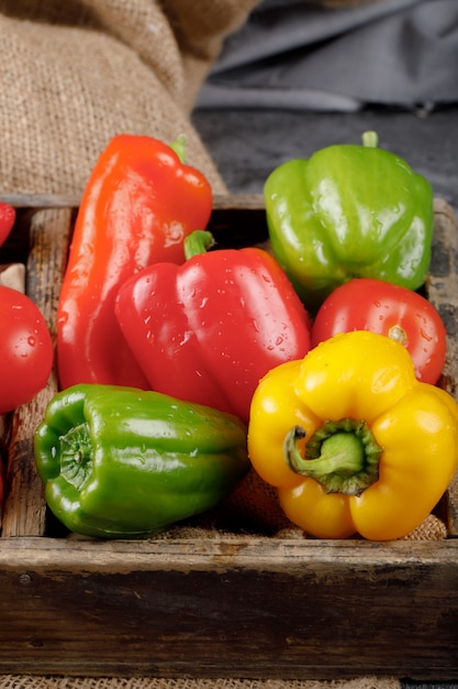 Color bell peppers in a rustic tray with water drops on them.