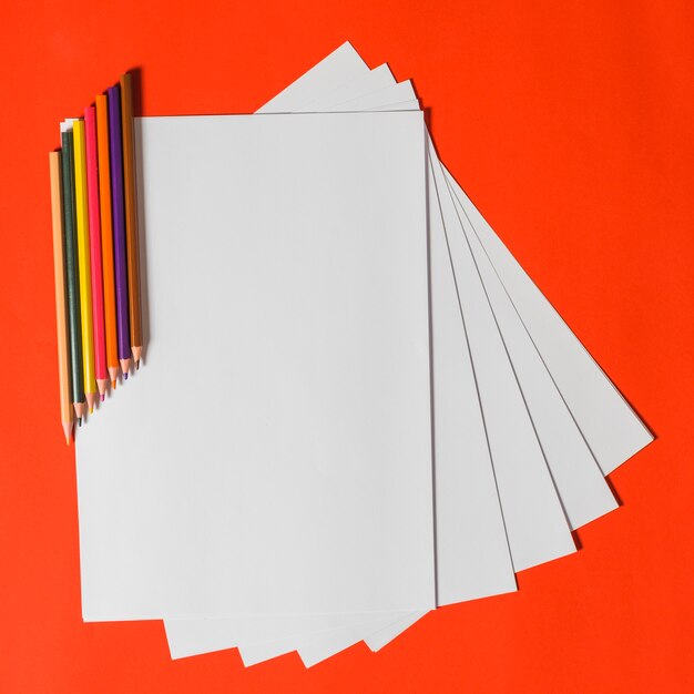 Color pencils and white papers over bright background