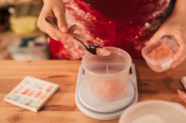 Free photo color powder in plastic bowl on measuring scale over the wooden desk