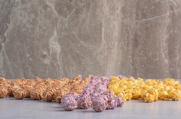 Color-sorted popcorn candy lined up on marble.