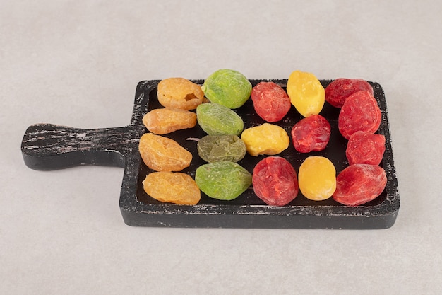 Бесплатное фото Цветные абрикосы и вишни на черном деревянном блюде.