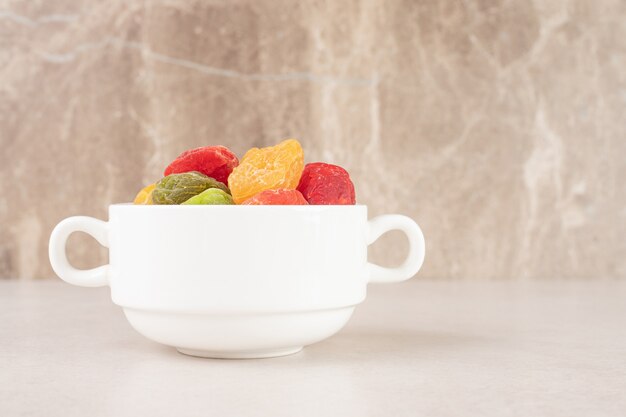 Colored apricots and cherries in a ceramic cup.