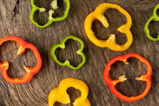 Free photo colored bell pepper slided on wood background