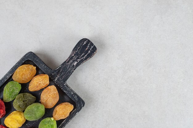 Colored dry cherry and apricots on a wooden platter.