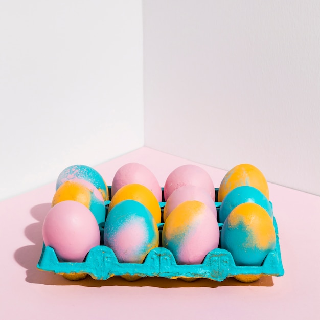 Бесплатное фото Цветные пасхальные яйца в яркой стойке на столе