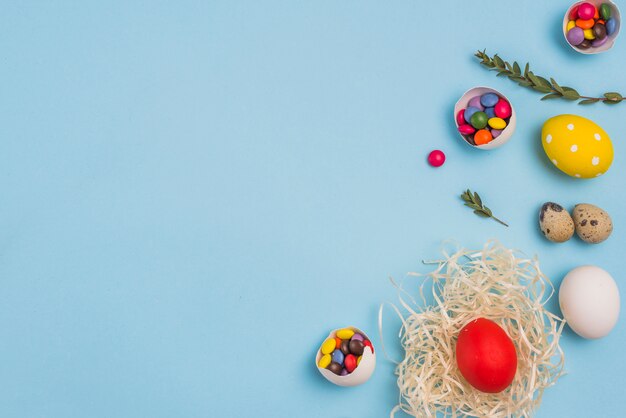 Colored egg in nest with candies on table