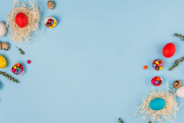 Бесплатное фото Крашеные яйца в гнездах с ветками растений и конфетами