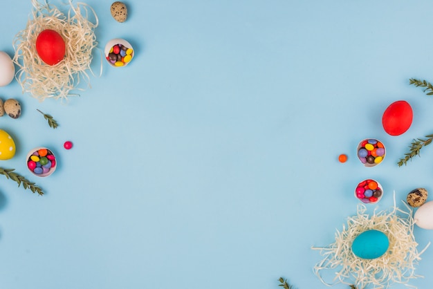 Colored eggs in nests with plant branches and candies