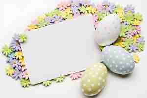 Foto gratuita uova colorate e fiori primaverili con tema pasquale carta bianca vuota