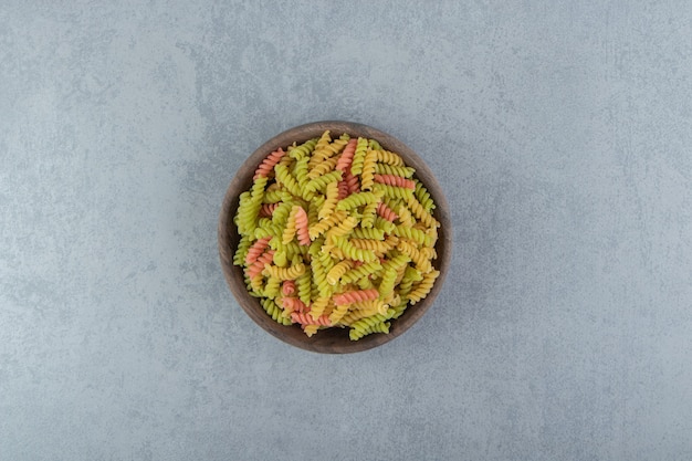 Colored fusilli pasta in wooden bowl.