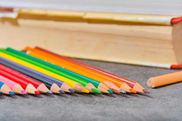 色鉛筆と明るい灰色のテーブル クローズ アップ セレクティブ フォーカスぼやけて背景に古い本学校教育概念レイアウト テンプレートに戻る