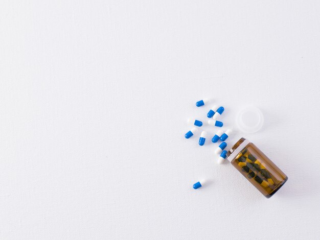 Colored pills a top view of spread pills and potions on white wall