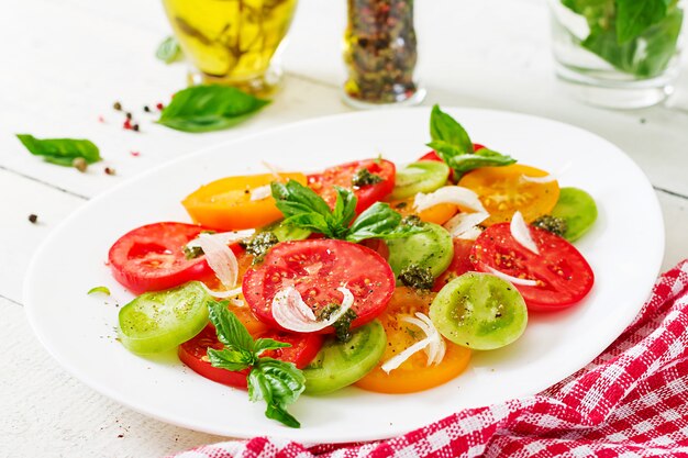 Colored tomato salad with onion and basil pesto. 