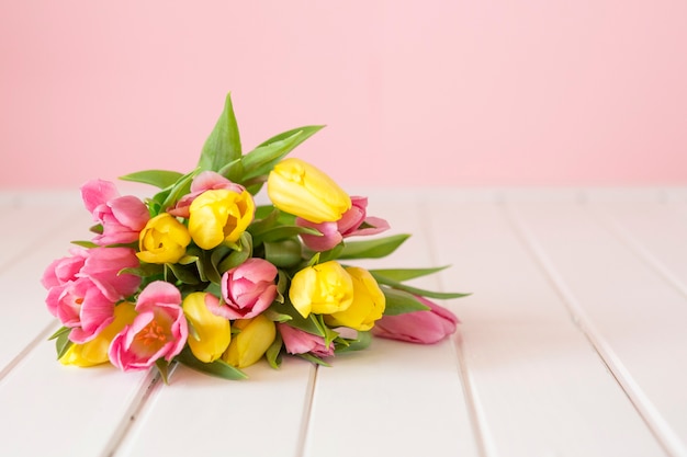 Colored tulips on white wooden surface