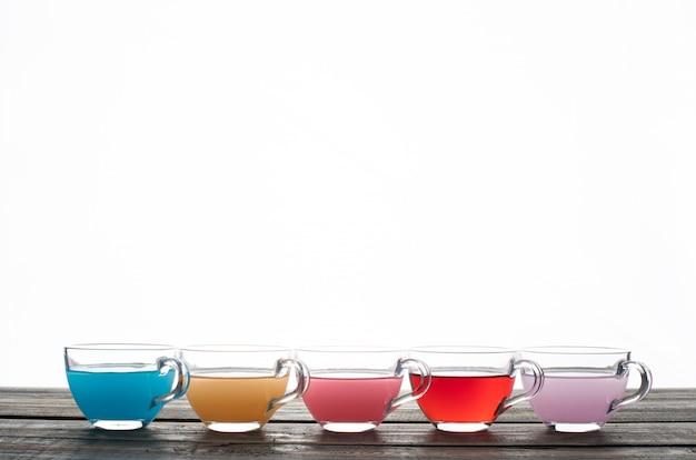 Colored water in cups on a white background. side view. space for text