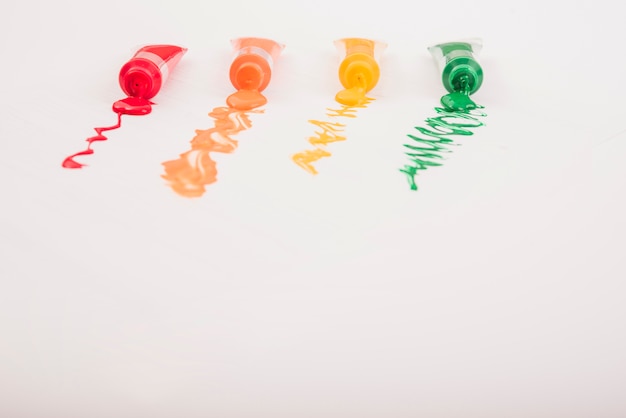 Colorful acrylic paints in tubes arranged in row over white background