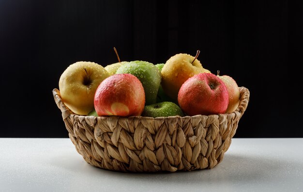 Colorful apples in a wicker basket on black and white