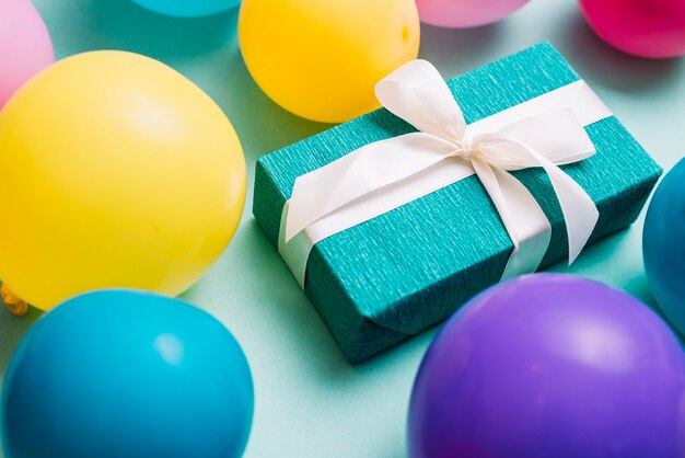 Colorful balloons around the gift box tied with white ribbon