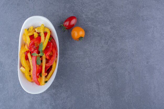 Colorful bell pepper salad with cherry tomatoes on blue surface