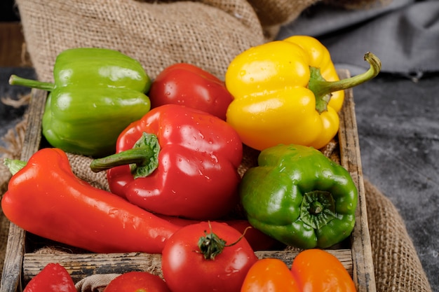 Free photo colorful bell peppers in a rustic tray. top view.