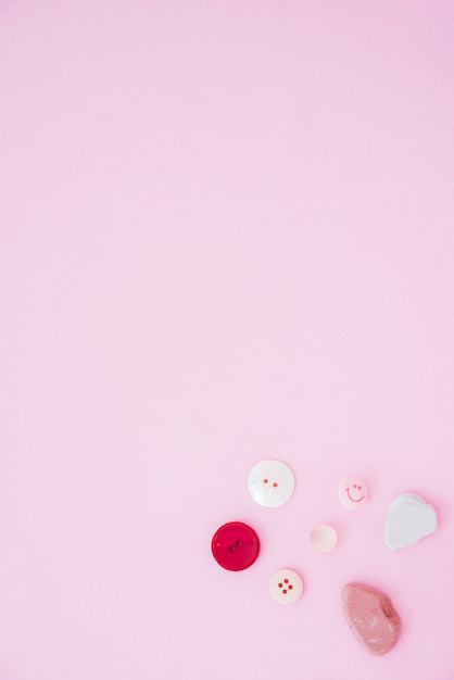 Colorful buttons and soap on the corner of the pink background