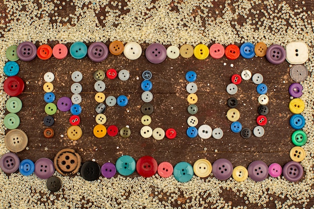 Free photo colorful buttons vintage for sewing hello word shaped around little yellow buttons on a wooden rustic desk