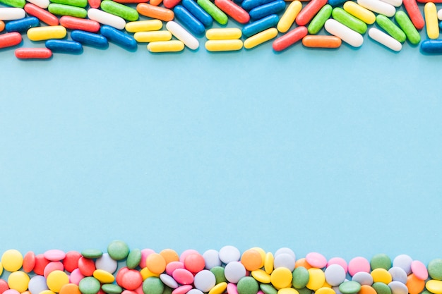 Бесплатное фото Красочные конфеты, формирующие верхнюю и нижнюю границы на синем фоне