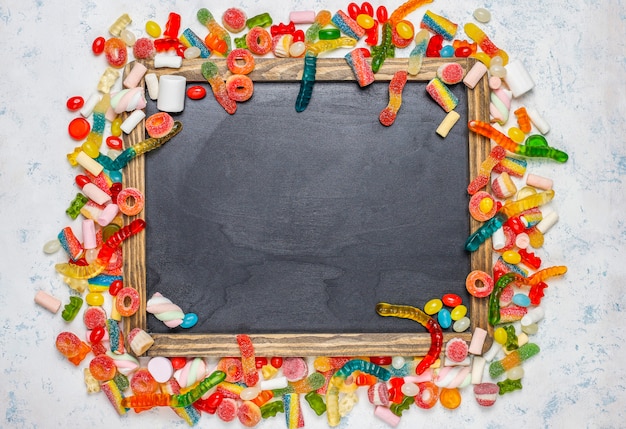 Foto gratuita caramelle colorate, gelatina, marshmallow sulla superficie della luce. vista dall'alto con spazio di copia