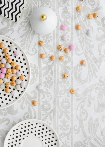 花柄のテーブルクロスの上の水玉プレートにカラフルなキャンディー