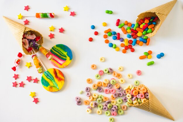 Colorful candies with waffle ice cream cone on white background