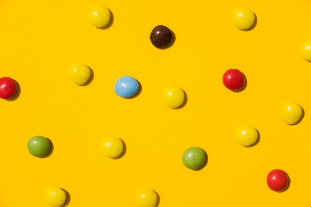 Free photo colorful candies on yellow backdrop