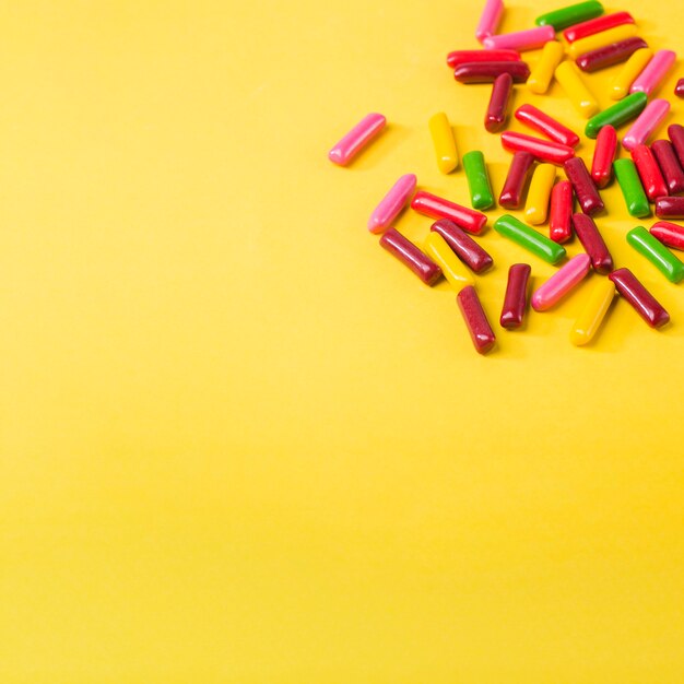 Colorful candies on yellow background