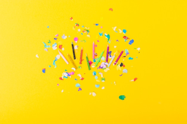 Colorful candles with confetti on yellow background