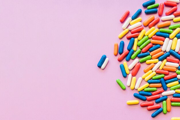 Colorful capsule candies on pink background