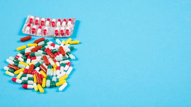 Colorful capsules and pill blister on blue background