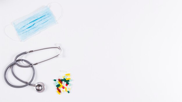Colorful capsules; stethoscope and mask on white background