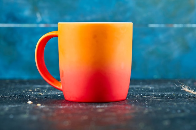 Free photo colorful ceramic mug isolated on blue desk.