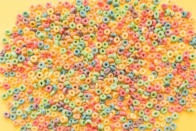 Free photo colorful cereal loop rings on yellow backdrop