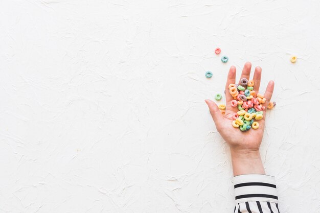 Colorful cereals on businesswoman's hand over white textured background