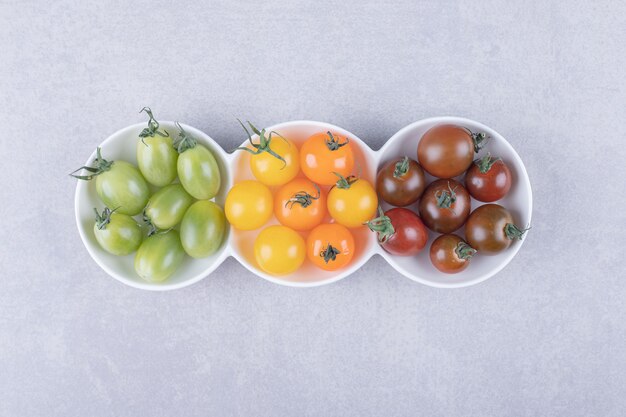 Colorful cherry tomatoes in white bowls.