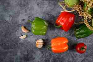 Free photo colorful chili peppers and garlics on a blue stone.