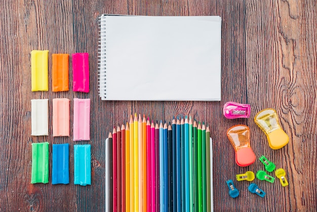 Colorful clay and pencil with white spiral notepad on wooden table