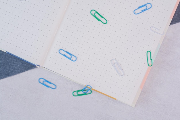 Colorful clips scattered around notebook on white surface.