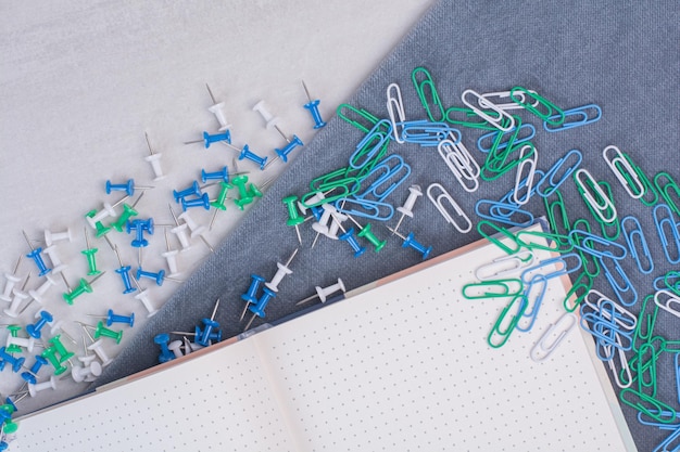 Colorful clips scattered around notebook on white table.