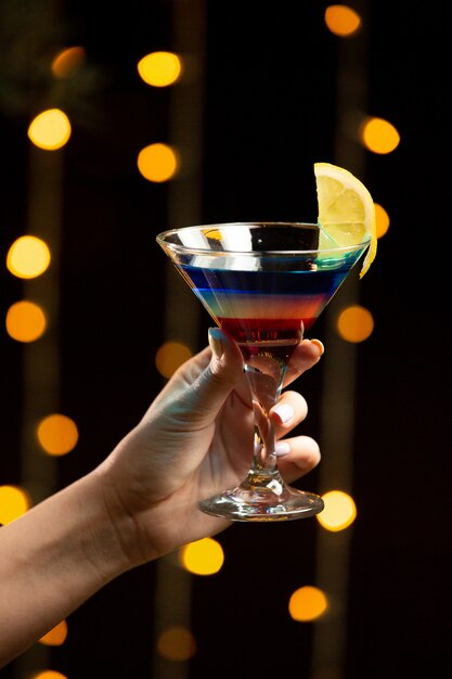 Colorful cocktail with lemon in the hand.