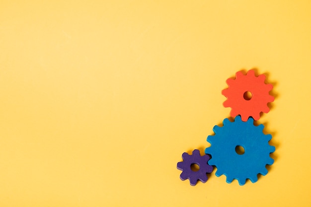 Free photo colorful cogwheels with yellow background top view